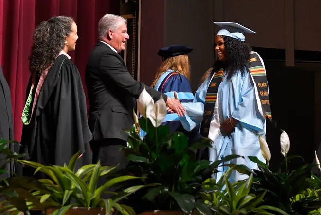 School board members congratulate a Riverside graduate